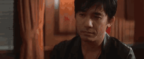 a man is sitting in a chair with his eyes closed and a foreign language written on his face .