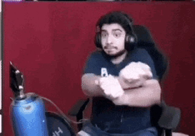 a man is sitting in a chair wearing headphones and a blue shirt .