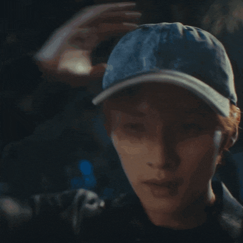 a man wearing a baseball cap adjusts his hat
