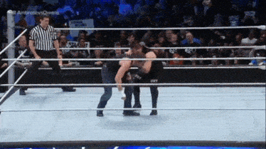 two men are wrestling in a ring with a referee and a sign that says ' squad rules ' on it
