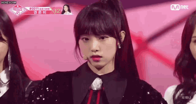 a girl with a ponytail is standing in front of a group of girls on a stage .