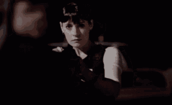 a woman in a fbi vest is standing in the dark looking at a man .