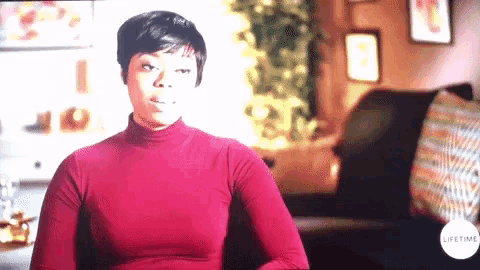a woman in a red turtleneck is sitting in front of a lifetime logo