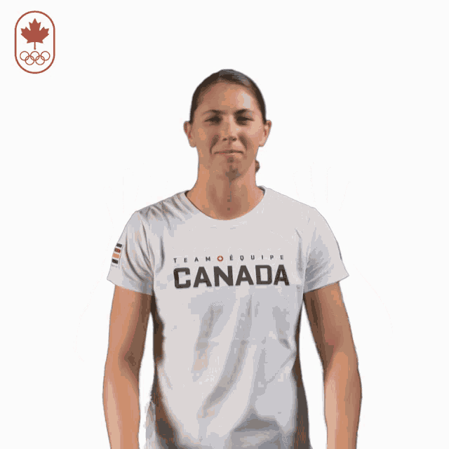 a woman wearing a canada t-shirt holds her hands up in the air
