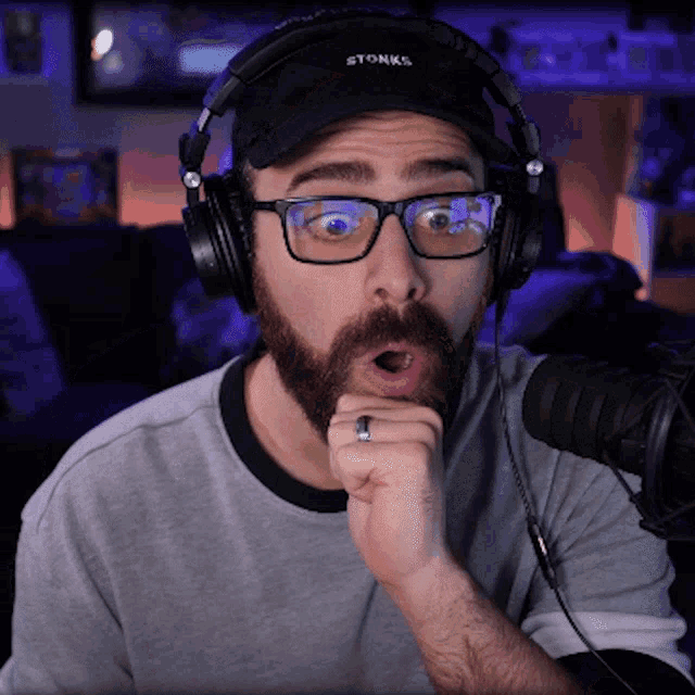 a man with a beard wearing headphones and a hat that says stonks