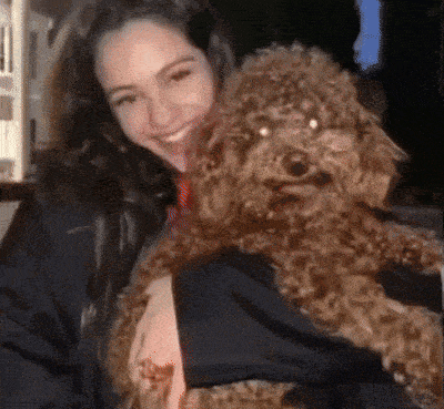 a woman is holding a small brown dog in her arms and smiling