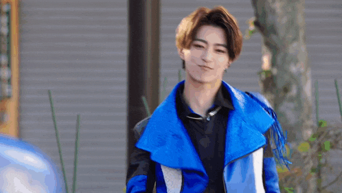 a young man wearing a blue jacket and a black shirt is walking down the street .