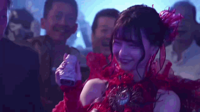 a woman in a red dress is smiling while holding a can of soda in her hand .