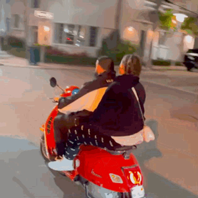 two people are riding a red scooter with a license plate that says ' eee ' on it