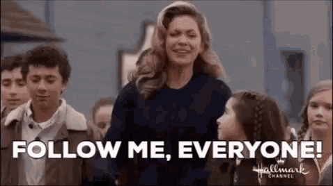 a woman is standing in front of a crowd of people with the words `` follow me , everyone '' .