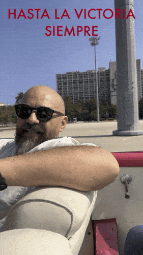 a man with a beard is sitting in a boat with the words hasta la victoria siempre written above him