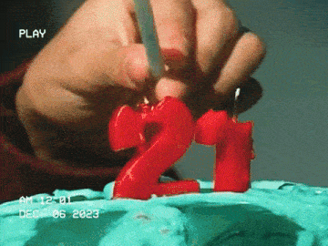 a person is lighting a number 21 candle on a birthday cake