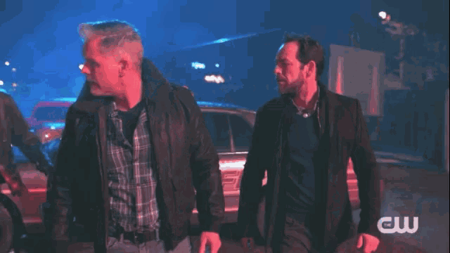 a group of men are walking down a street with a cw logo in the corner