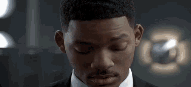 a man in a suit and tie is looking down with his eyes closed
