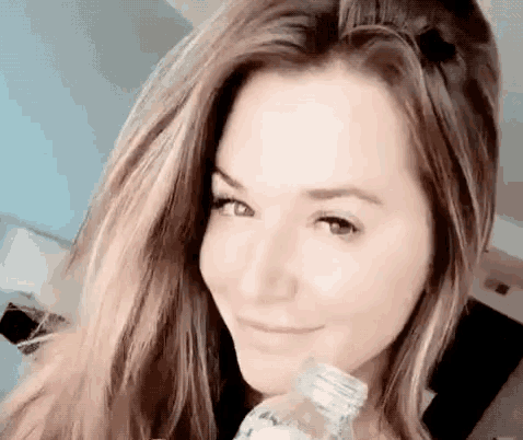 a woman is holding a bottle of water in her hand and smiling