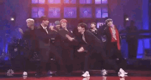 a group of people are standing on a stage holding microphones and dancing .