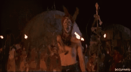a naked woman is standing in front of a fire in a dark room .