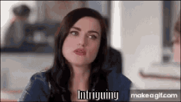 a woman is sitting at a table and making a funny face while talking .