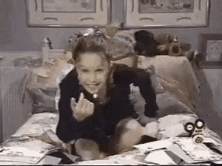a young girl is sitting on a bed with a pile of papers on it .