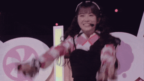 a girl wearing a headband and a microphone smiles while dancing on a stage
