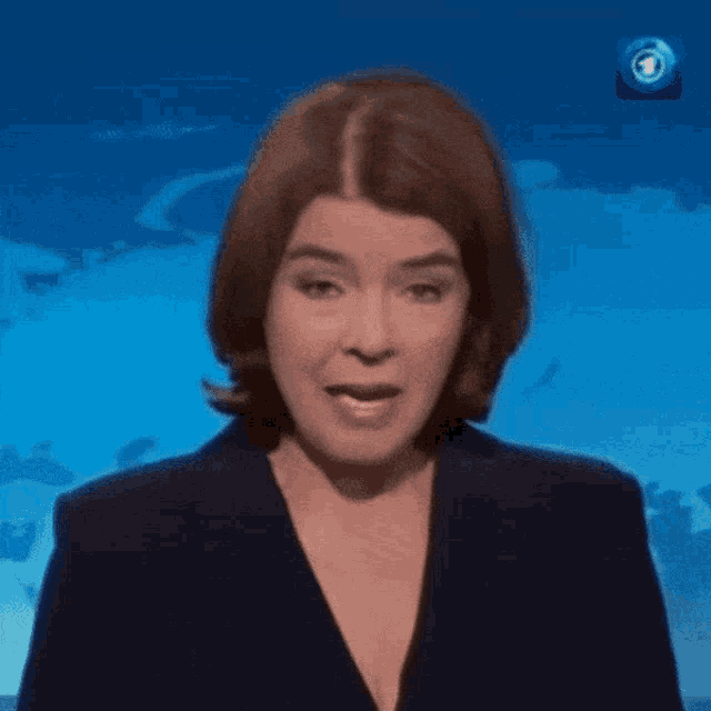 a woman in a blue jacket says sh in front of a world map
