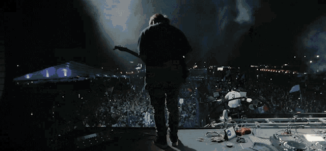 a man is playing a guitar in front of a crowd