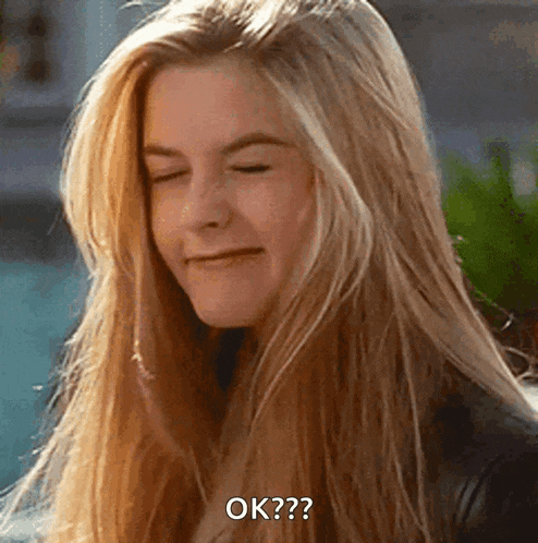 a woman with long blonde hair is smiling with her eyes closed and the words ok ? on her face .