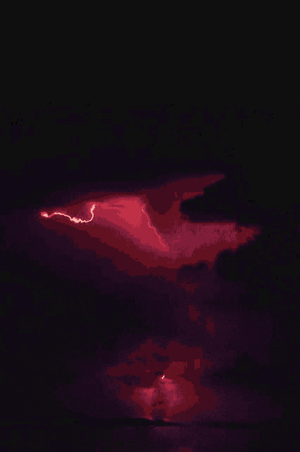 a red lightning bolt strikes the ground in the night sky