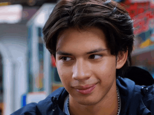 a close up of a young man 's face with a blue jacket on