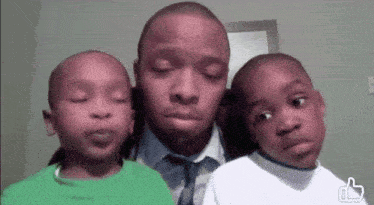 a man and two young boys are posing for a picture with a thumbs up sign in the corner