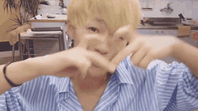 a man with blonde hair making a heart shape with his hands