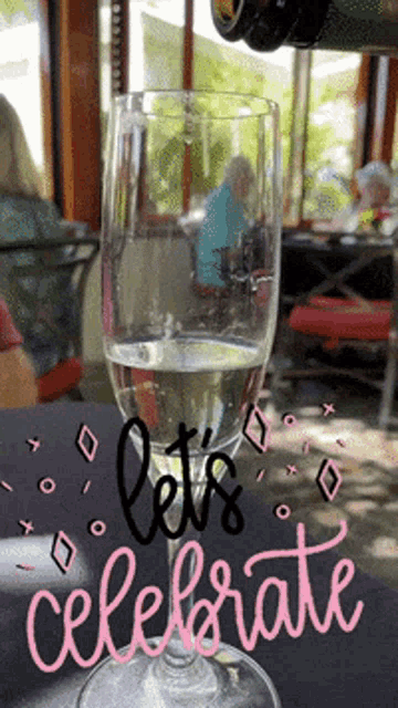 a glass of wine with the words " let 's celebrate " written on it