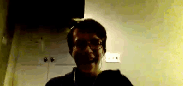 a man wearing headphones looks at the camera with a yellow background