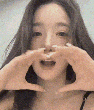 a close up of a woman making a heart with her hands .