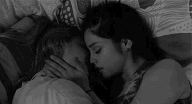 a black and white photo of two women hugging each other .