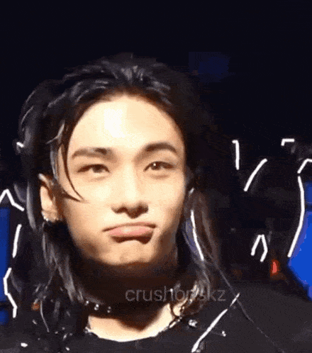 a close up of a young man with long hair making a face .