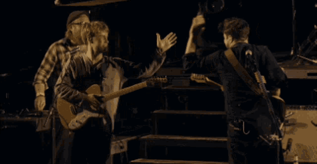 a man playing a guitar and another man playing a bass are giving each other a high five