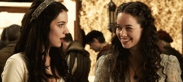 two women are standing next to each other smiling and looking at each other