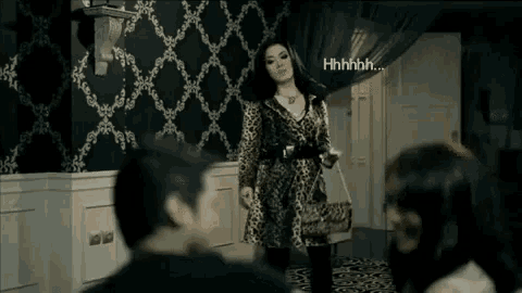 a woman in a leopard print dress is standing in a room with a man and a woman .