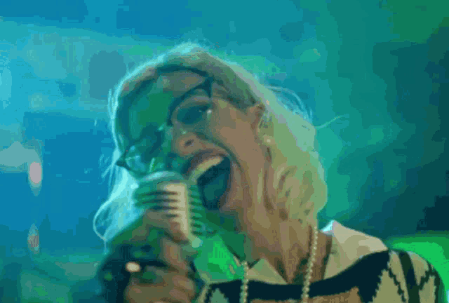 a woman singing into a microphone with a blue background