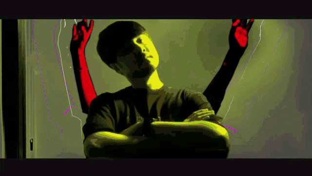 a man stands with his arms crossed in front of a yellow and purple background with the letter n in the corner