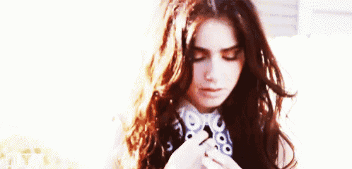 a woman with long hair is wearing a ring and looking down .