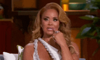 a woman in a white dress is sitting on a couch and making a face .