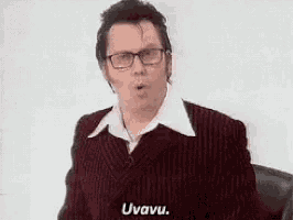 a man wearing glasses and a suit is making a funny face .