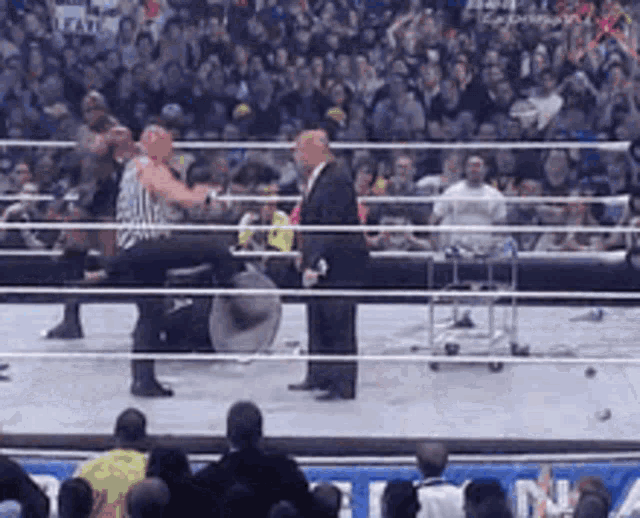 a man in a suit is standing in a wrestling ring with a crowd watching