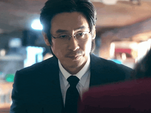 a man in a suit and tie looks at a woman in a red jacket