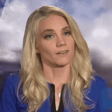 a woman with blonde hair is wearing a blue jacket and black shirt .