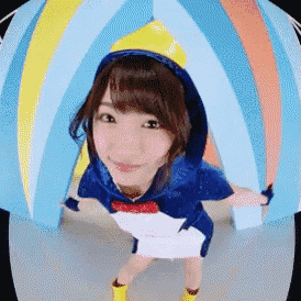 a woman in a penguin costume is standing in front of a colorful ball .