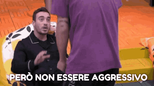 a man in a purple shirt is standing next to another man with the words pero non essere aggressivo above him