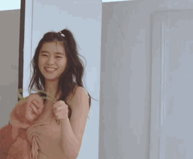 a woman is holding a flower in her hand and smiling .
